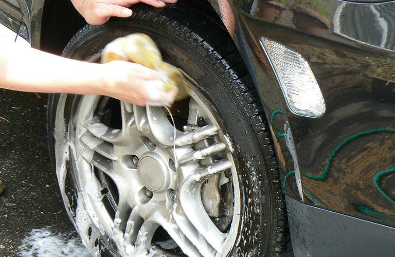 person washing vehicle tire